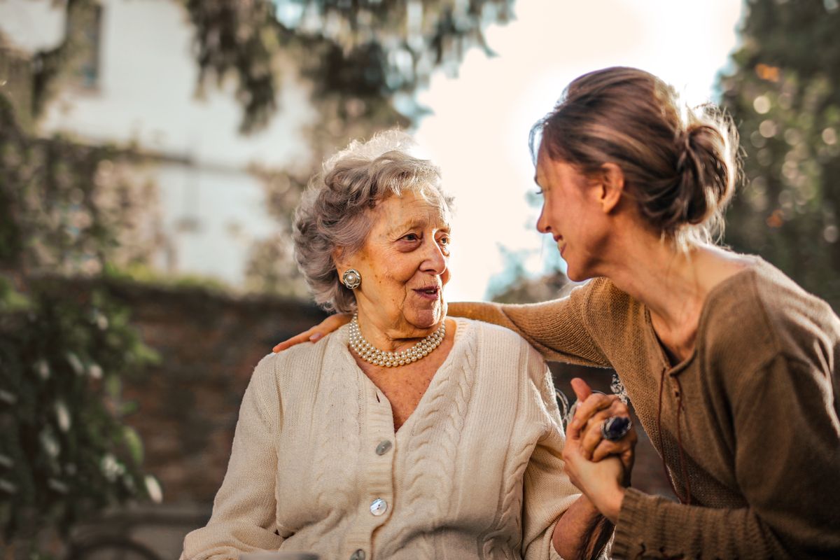 An older woman talking with a family caregiver outdoors